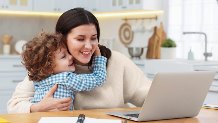 Smiling,Woman,Working,With,Laptop,And,Her,Son,At,Wooden