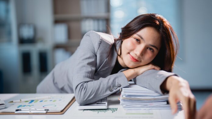 Young,Asian,Businesswoman,Resting,Her,Head,On,A,Large,Pile